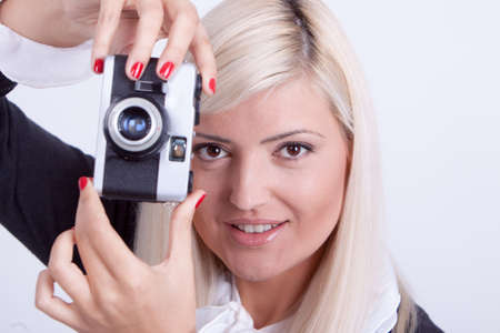 Blonde woman photographing over white background