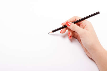 Woman writing with wooden pencil on white sheetの写真素材