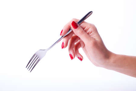 Woman hand with red manicure holding forkの写真素材