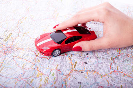 Toy red car on female hand on white background