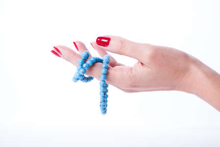 Beautiful woman hands with red manicure holding color pearl necklaceの写真素材