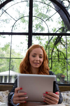 Pretty girl posing with a tablet in cafe