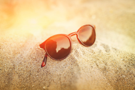 Sunglasses on the golden sand with reflections in the glass. Seascape ocean and beautiful beach paradise. Summer vacation concept. Close up.の写真素材