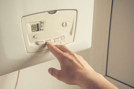 Male hand setting temperature on a heating boiler construction. Close up shot.の写真素材