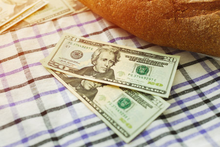 Two 20 dollars bills next to fresh bread on the table. Lack of bread, the concept of a world food...