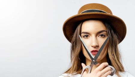 A woman wearing a hat looking through scissors