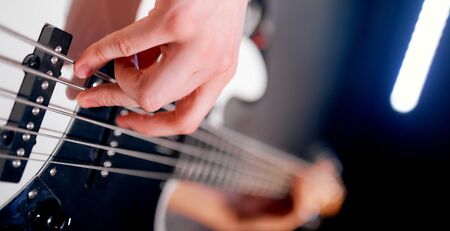 A close up of a person holding and playing a bass guitar