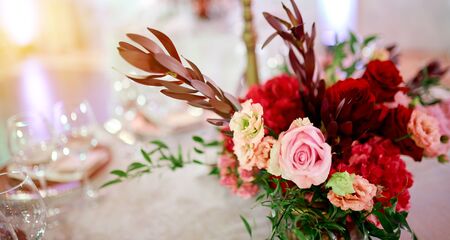 served table with plates ant glasses decorated by flowers