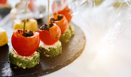 stuffed little tomatoes on a black tray Canapes Catering