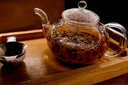 brewed tea in a glass kettle on a traditional wooden tray with pialの写真素材