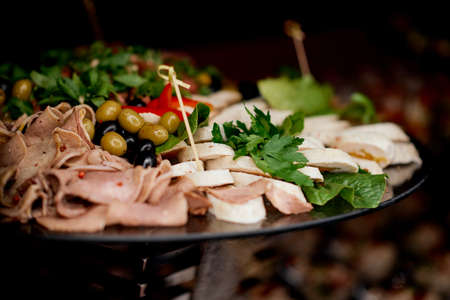 meat delicatessen plate arranged with cherry tomato, black and green olives and parsley. High...
