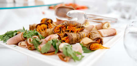 jerky on a white plate on a white table with tongs for food . High quality photo