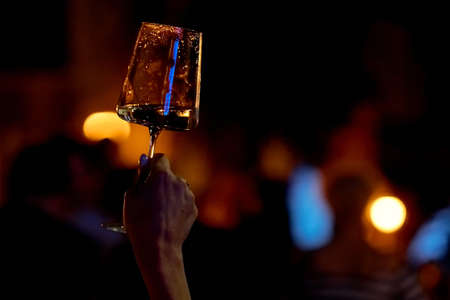 Hand held a glass of wine under night light.の写真素材