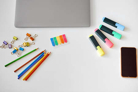On the table are various colored stationery laptop and phoneの写真素材
