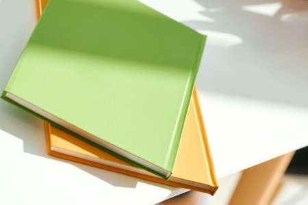 Two notepads, green and orange, lie on the edge of the white desktop