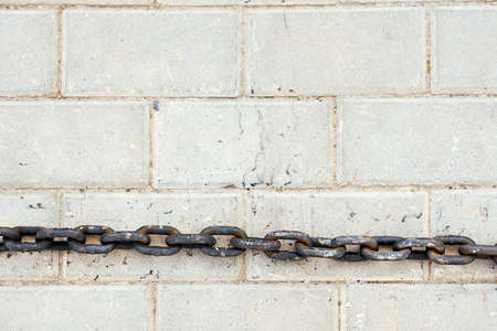 old rusty chain lies on a flat white tile