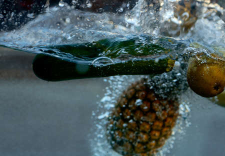 in the water dropped eggplant pear and pineapple, shooting from the sideの写真素材