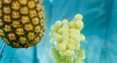 pineapple and grapes dipped in water at the same timeの写真素材