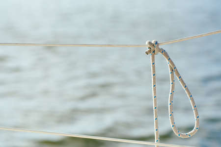 Knot on the fence of the yacht board against the background of the ocean sea waterの写真素材
