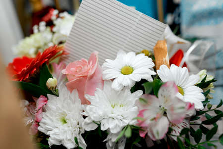 bouquet of white daisies with scarlet and pink roses and an empty card. High quality photoの写真素材