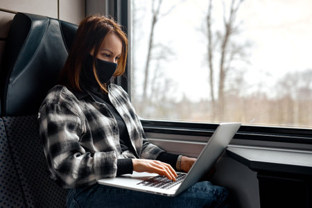 Focused Woman Typing on Laptop in Train.