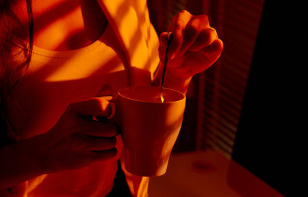Closeup of Woman Stirring Mug in Cozy Office Lighting.の写真素材