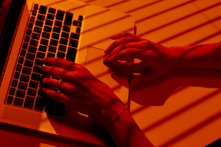 Woman Working on Laptop with Blinds Shadows in Warm Light.