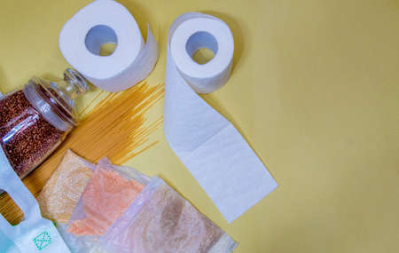 Food items for donation, on a yellow background. Buckwheat in containers for bulk products. Macaroni, cereals in a cellophane bag. With space for text. Vertical photo.の写真素材