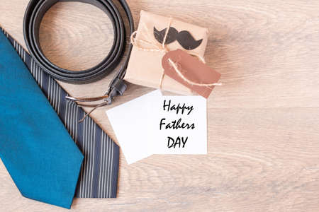 Two blue ties, leather, black belt, gift in craft paper on a wooden background. Black mustache. Wooden background. The view from the top. Space for textの写真素材