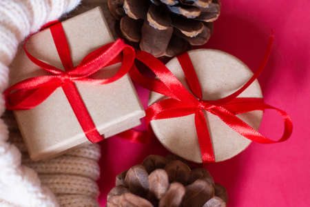Christmas gifts from a round and square box, tied with a red ribbon on a red background with wooden...
