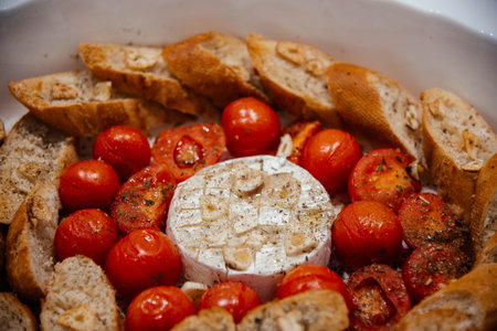 Camembert cheese baked with tomatoes and baguette, herbs and garlic. An excellent appetizer for wine. View from aboveの写真素材
