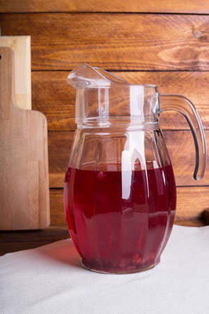 Fresh and healthy red Fruit juice drink  in a glass jug on the wooden brown table background. Side view.の写真素材