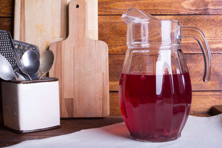 Fresh and healthy red Fruit juice drink  in a glass jug on the wooden brown table background. Side view.の写真素材