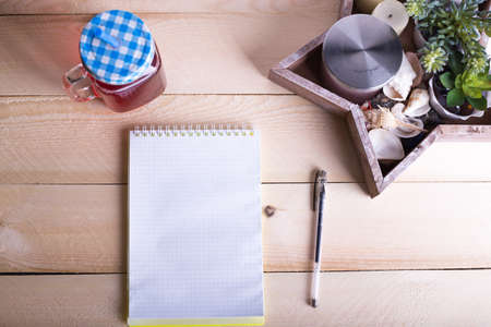 Opened notebook with a cup of tea, wooden star and a flower on wooden table. Top view. Writing concept.の写真素材
