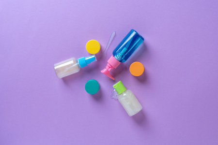 Set of full plastic travel bottles on lavender background. Travel kit with approved for airplane hand luggage bottle container size. Travel containers with colorful tops.の写真素材