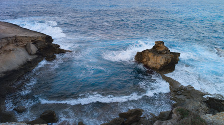 Dramatic Rocky Coast Framing Turbulent Sea with Waves and Foamの写真素材