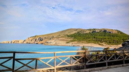 Scenic coastal view with turquoise sea, rocky hills and wooden fenceの写真素材
