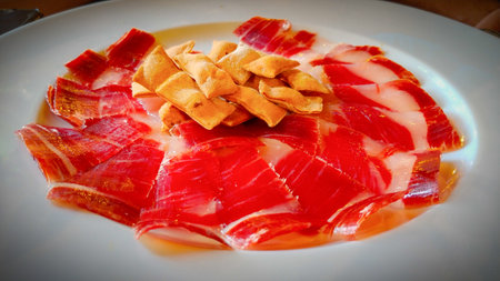 Slices of ham with crackers on a white plate