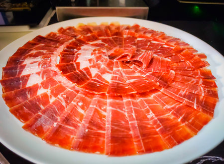 Slices of serrano ham on a white plate in a restaurantの写真素材