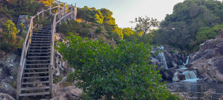 Staircase leading to a waterfall in the mountains at sunset.