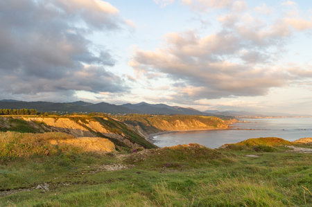 Scenic view of the coastline at sunset with clouds in the sky