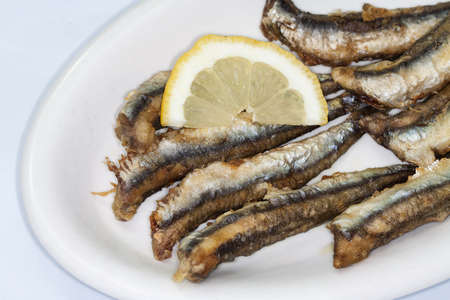 Dish of Fried anchovies with lemon on  white backgroundの写真素材