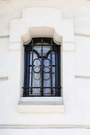 Window bars covering an old boarded and stuccoed window