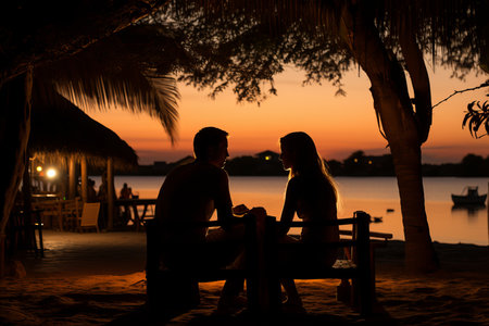 A couple enjoys a candlelit dinner on a serene Indian beach, savoring a sumptuous seafood spread as the sun sets over the ocean.の素材