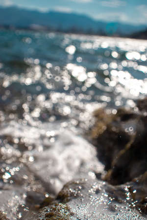 Out of focus seashore, rocks and water creating many beautiful bokeh shapesの写真素材