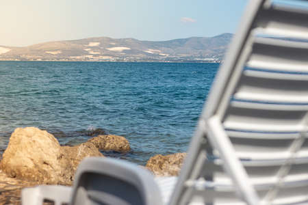 Bright blue sea of the adriatic in focus with a bed bench in foreground, concepts of vacation, summer and travelの写真素材