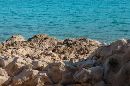 Stone rocks on the shore of split, bright blue warm sea waterの写真素材