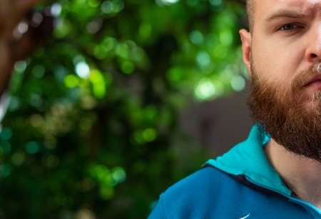 Half the head and torso of a bearded bald man wearing a hoodie looking straight at the camera. Serious sad look, thinking about somethingの写真素材