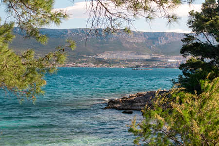 Sea view of a hidden beach in Split, Croatia. Rocks on the bright blue sea. Mountains in distanceの写真素材