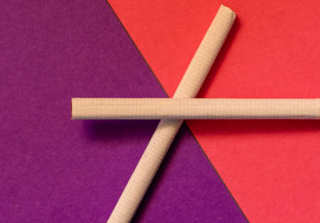 Two cigarettes forming a cross shape on the border of pink and purple backgroundsの写真素材